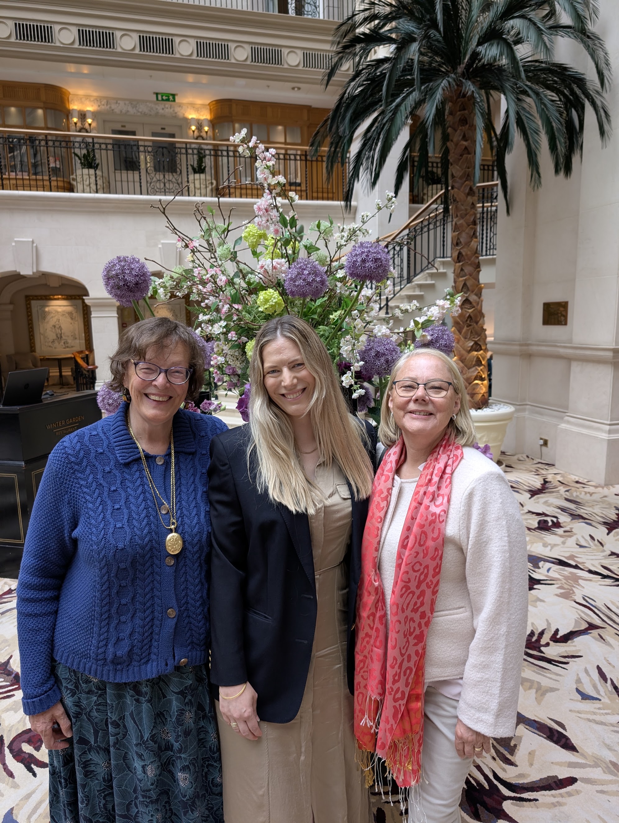Sarah with two family members in front of a floral display